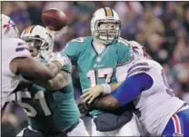  ?? BILL WIPPERT/ THE ASSOCIATED PRESS ?? Miami Dolphins quarterbac­k Ryan Tannehill is hit by Buffalo Bills defensive tackle Marcell Dareus while throwing a pass Thursday.