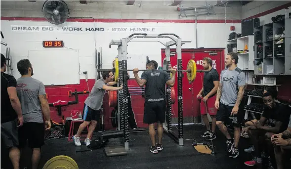  ?? PHOTOS: TYLER ANDERSON/ NATIONAL POST ?? Mike Cammalleri, centre left, of the New Jersey Devils, watches an impressive feat of strength from Devante Smith-Pelly, of the Montreal Canadiens, during a pre-season training session with Matt Nichol, who co-invented the workout supplement drink...