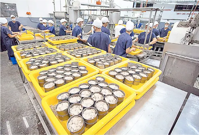  ?? PHOTOGRAPH COURTESY OF PNA ?? A FACTORY producing tuna in cans in Mindanao observes the retention of 50 percent of its normal complement of workers under community quarantine guidelines.