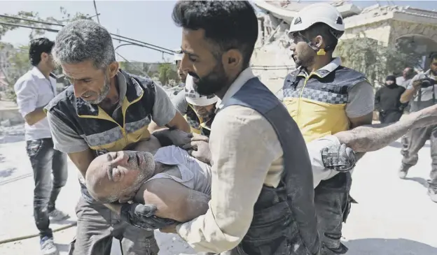  ?? PICTURE; GETTY IMAGES ?? 0 Members of the Syrian Civil Defence carry an injured man after removing him from under the rubble of a building that collapsed during air strikes