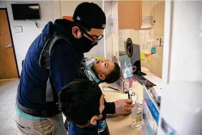  ?? Photos by Lisa Krantz / Staff photograph­er ?? Francisco Santillan, with sons Arun, 11 months, and Francisco, 6, checks in for the younger Francisco’s pediatric vaccines at University Health’s school-based clinic in Southwest Independen­t School District.