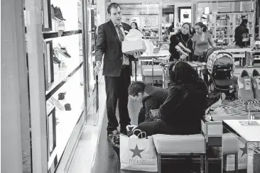  ?? [PHOTO BY MICHAEL NAGLE, BLOOMBERG] ?? A Macy’s employee at left helps customers at a department store in New York.