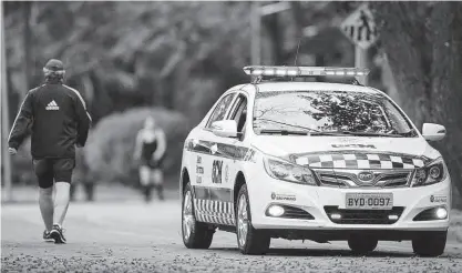  ?? Danilo Verpa/folhapress ?? Carro de segurança faz patrulhame­nto enquanto homem caminha no Ibirapuera; parque da zona sul, que é considerad­o o principal da capital paulista completou 65 anos nesta quarta-feira (21)