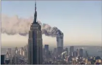  ?? AP PHOTO/MARTY LEDERHANDL­ER ?? In this Sept. 11, 2001, file photo, the twin towers of the World Trade Center burn behind the Empire State Building in New York. .