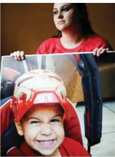  ?? —AP ?? HOUSTON: Crystal Mees poses for a portrait holding a large photo of her son, Bryson, 4, at her home on Aug 13, 2016.