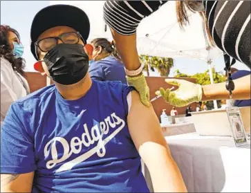  ?? CARLOS CORTEZ Al Seib Los Angeles Times ?? receives a COVID-19 vaccine from registered nurse Janice Taylor last month at a walk-up mobile clinic in Los Angeles. Nearly 50% of California­ns have received at least one COVID-19 vaccine dose.