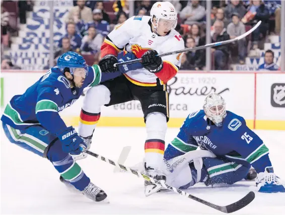  ?? JONATHAN HAYWARD, THE CANADIAN PRESS ?? Canucks defenceman Michael Del Zotto, left, battles Flames’ Mikael Backlund in front of Vancouver goalie Jacob Markstrom Wednesday night at Rogers Arena in Vancouver. The Canucks won the game 5-2.