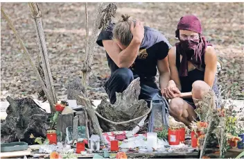  ?? FOTO: DPA ?? Waldbesetz­er trauern an der Unfallstel­le im Hambacher Forst. Sie legten Blumen nieder und zündeten Kerzen an.