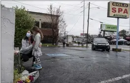  ?? BEN GRAY — THE ASSOCIATED PRESS ?? Mallory Rahman and her daughter Zara Rahman, 4, who live nearby, pause after bringing flowers to the Gold Spa massage parlor in Atlanta, Wednesday afternoon, the day after eight people were killed at three massage spas in the Atlanta area.