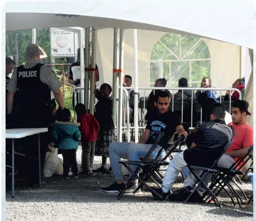  ?? PHOTO CAMILLE GARNIER ?? Des migrants sont pris en charge par les agents de la GRC après avoir passé la frontière à Saint-bernard-de-lacolle.