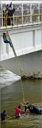  ??  ?? A migrant makes a perilous descent from the bridge, top, in a bid to make the river crossing on a raft DANGER DROP: