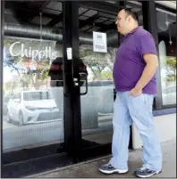  ?? AP/ ALAN DIAZ ?? Jose Espinosa looks into a closed Chipotle restaurant on his lunch break on Monday in Miami Lakes, Fla. Chipotle restaurant­s across the United States opened later than usual Monday as workers gathered to discuss the chain’s recent food safety scares.