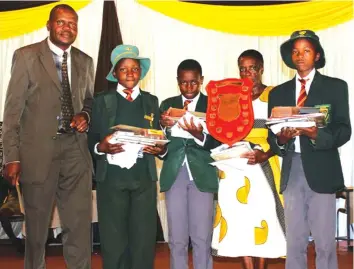  ??  ?? Dr Paul Mupira (left) NMMZ Regional Director Eastern region presenting the winner's shield to the 2017 provincial winners John Primary School