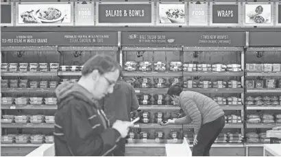  ?? ELAINE THOMPSON/AP ?? Shoppers roam through an Amazon Go store, open to Amazon employees, in Seattle. Amazon is a expert at using data on past shopping and browsing to prod consumers into buying more. That skill is certain to figure greatly in the strategy behind its...