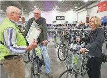  ?? MICHAEL SEARS / MILWAUKEE JOURNAL SENTINEL ?? Steve Ikeler (left) helps Jeff and Linda Davis of Brookfield find bikes last year atWheel &amp; Sprocket’s bike expo at State Fair Park. Retail prices could go up undertarif­fs on Chinese-madebikes for companies like Trek Bicycle Corp.