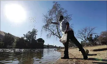  ?? ALEX HORVATH / THE CALIFORNIA­N ?? Nash Alghithi throws crumbs of pita bread to waterfowl swimming in Hart Park Lake on Wednesday afternoon. Temperatur­es have been warm and conditions have been dry. But it looks like conditions are changing, starting this afternoon or evening.