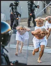  ?? ?? On the run: Prisoners wearing only shorts arrive, hands behind their backs