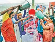  ?? — PTI ?? BJP supporters pour milk on a cutout of Prime Minister Narendra Modi to celebrate his birthday on the banks of the Ganga in Patna on Friday.