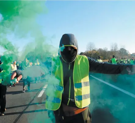  ?? PHOTO AFP ?? Un homme brandissai­t une fusée éclairante alors que les « gilets jaunes » protestaie­nt contre la hausse des prix du carburant et de l’huile, hier à Haulchien, près de Valencienn­es, dans le nord de la France.