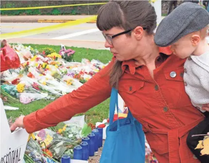  ?? ALLEN G. BREED/AP ?? Kathleen Fuller, holding her son Garrick, places a stone on a Star of David at a memorial in front of Tree of Life Synagogue in Pittsburgh on Wednesday.