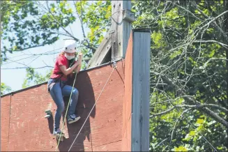  ??  ?? Miranda Pineda, 13, climbs to the top of a rock wall while at Camp Hope for Kids in Schwenksvi­lle.