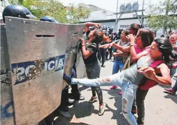  ?? AP, Reuters ?? ■ ■ Relatives of prisoners fight with a lineup of police officers as they wait for informatio­n about prisoners outside a police station in Valencia, Venezuela on Wednesday. Right: Relatives of inmates held at the General Command of the Carabobo Police...