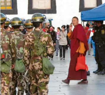  ?? Archivfoto: dpa ?? Die allgegenwä­rtige Staatsmach­t zeigt Präsenz in Lhasa, während ein buddhistis­cher Mönch über den Platz eilt.