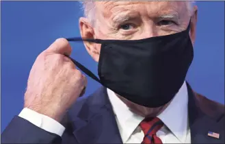  ?? Alex Wong / Getty Images ?? President-elect Joe Biden takes off his mask as he lays out his plan on combating the coronaviru­s Saturday in Wilmington, Del.