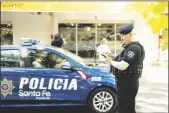  ?? AP PHOTO/SEBASTIAN LOPEZ BRACH ?? Police gather outside the Unico supermarke­t, a grocery chain owned by soccer player Lionel Messi’s in-laws, after it was shot at in Rosario, Argentina, on Thursday.