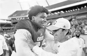  ?? MICHAEL LAUGHLIN/SOUTH FLORIDA SUN SENTINEL ?? Cardinal Gibbons offensive lineman Gerald Mincey celebrates with his head coach, Matt DuBuc, after the Chiefs won the 5A state final over North Marion at Camping World Stadium.