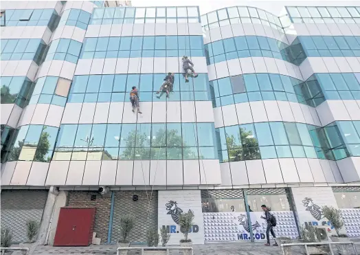  ??  ?? SCRUBBING UP WELL: In a city transforme­d from rubble, workers clean the windows of a building in Kabul late last month.