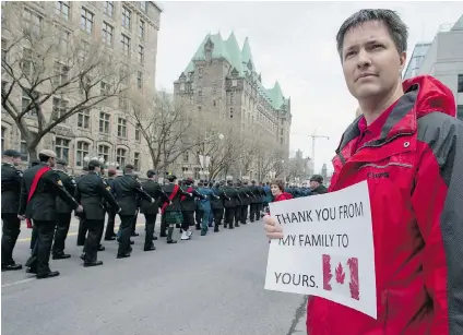  ?? JUSTIN TANG/ THE CANADIAN PRESS ?? Sam Lang holds a sign thanking Canadian Forces members as they march past during the National Day of Honour in Ottawa on Friday. The day of remembranc­e also included a parade of veterans, police and civilians who served in Afghanista­n.
