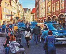  ?? AFP ?? People walk past police cars in Muenster, western Germany, ■ where several people were killed and others injured when a car ploughed into pedestrian­s yesterday.