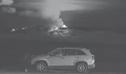  ?? GREGORY BULL/AP ?? Hundreds of people in their cars line Saddle Road, which connects the east and west sides of Hawaii’s Big Island, as lava flows down the side of Mauna Loa volcano near Hilo.