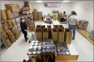  ?? STEVE HELBER - THE ASSOCIATED PRESS ?? Hands Across Middlesex Food Pantry volunteers pack bags of food for their food pantry distributi­on Monday April 27, in Locust Hill, Va. The rural food pantry has seen its membership spike in the weeks since the coronaviru­s pandemic has walloped the economy.