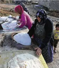  ??  ?? AFP Khadija, a 75- year- old Kurdish woman who evacuated her home due to shelling by regime forces, bakes bread outside a house in Khirbet Al Joz.