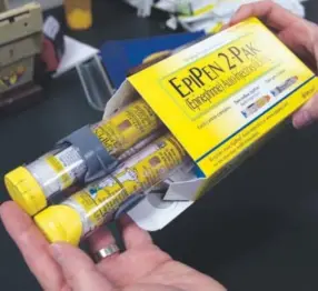  ??  ?? A pharmacist holds a package of EpiPens, an epinephrin­e autoinject­or for the treatment of allergic reactions. Rich Pedroncell­i, Associated Press file