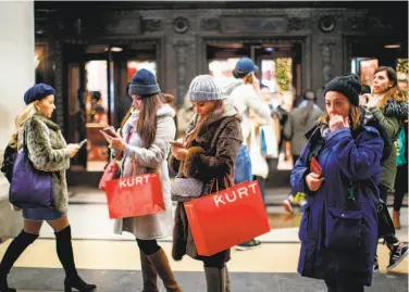  ?? Tolga Akmen / AFP / Getty Images ?? Shoppers scan their smartphone­s in the main retail district on Oxford Street in London less than two weeks before Christmas. Retailers are using apps to improve shoppers’ experience in stores.