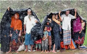  ??  ?? Hiding from the rain: Rohingya refugees sheltering from the rain at a camp in Cox’s Bazar, Bangladesh. — Reuters