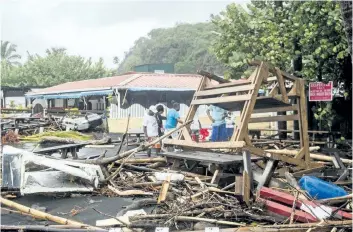  ?? LIONEL CHAMOISEAU/GETTY IMAGES ?? People stand next to debris at a restaurant in Le Carbet on Tuesday, on the French Caribbean island of Martinique, after it was hit by hurricane Maria.