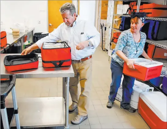  ?? Eduardo Contreras ?? San Diego Union-tribune Louis Vener picks up hot meals from Foodmobile distributi­on specialist Darla Marcus at Jewish Family Services for delivery to San Diego seniors and shut-ins.