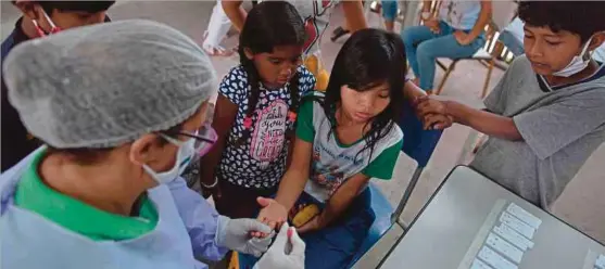  ?? (Foto AFP) ?? Kakitangan hospital melakukan ujian saringan COVID-19 terhadap kanak-kanak di kem suku Sao Mata Verde Bonita, Rio de Janeiro, Brazil.