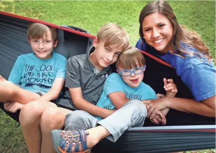  ?? HELEN COMER//USA TODAY NETWORK - TENNESSEE ?? MTSU alum Missy Wood with the Kellum boys she babysits, from left, Owen, 9, Aidan, 11, and El, 7, in the family’s backyard in Murfreesbo­ro on June 18. Wood has been looking for work, since April before her MTSU graduation in May. After the pandemic hit, job postings for her field seemed to disappear.