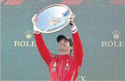  ?? JOEL CARRET ?? Carlos Sainz alza el trofeo de ganador del Gran Premio de Australia, con la mirada puesta en el cielo.