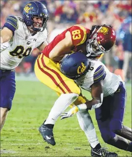  ?? Luis Sinco Los Angeles Times ?? THE TROJANS’ Josh Falo holds on to a catch while being tackled by California defenders Evan Weaver, left and Jaylinn Hawkins on Saturday night.