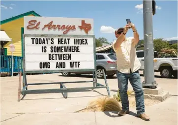  ?? JAY JANNER/AUSTIN AMERICAN-STATESMAN ?? Mitchell Clearman takes a photo of a sign Thursday at El Arroyo restaurant in Austin, Texas. A heat wave that’s already persisted more than a week continues to bake the United States, Asia and Europe.