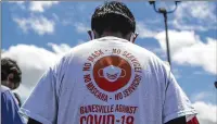  ??  ?? ◄ A man wears a T-shirt printed in Spanish and English at a COVID-19 testing site in the parking lot of La Flor de Jalisco #2 in Gainesvill­e on Friday.