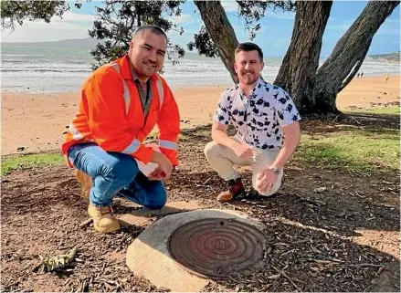  ?? ?? Watercare project manager Johan Gerritsen and Auckland Councillor Richard Hills kneel next to one of the manholes that was rehabilita­ted as part of the Takapuna Foreshore Beach Pipeline relining works.