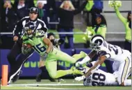  ?? SCOTT EKLUND / AP ?? Seattle Seahawks’ Tyler Lockett lunges for a touchdown in front of a pair of Los Angeles Rams defenders during the second half of Thursday’s NFL clash in Seattle. Lockett had 130 yards receiving as the Seahawks clinched the NFC West title with a 24-3...