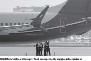  ?? AP ?? Ground crew chat near a Boeing 737 Max 8 plane operated by Shanghai Airlines parked on tarmac at Hongqiao Airport in Shanghai, China, on Tuesday, March 12, 2019. uS aviation experts on Tuesday joined the investigat­ion into the crash of an Ethiopian Airlines jetliner that killed 157 people, as a growing number of airlines grounded the new Boeing plane involved in the crash.